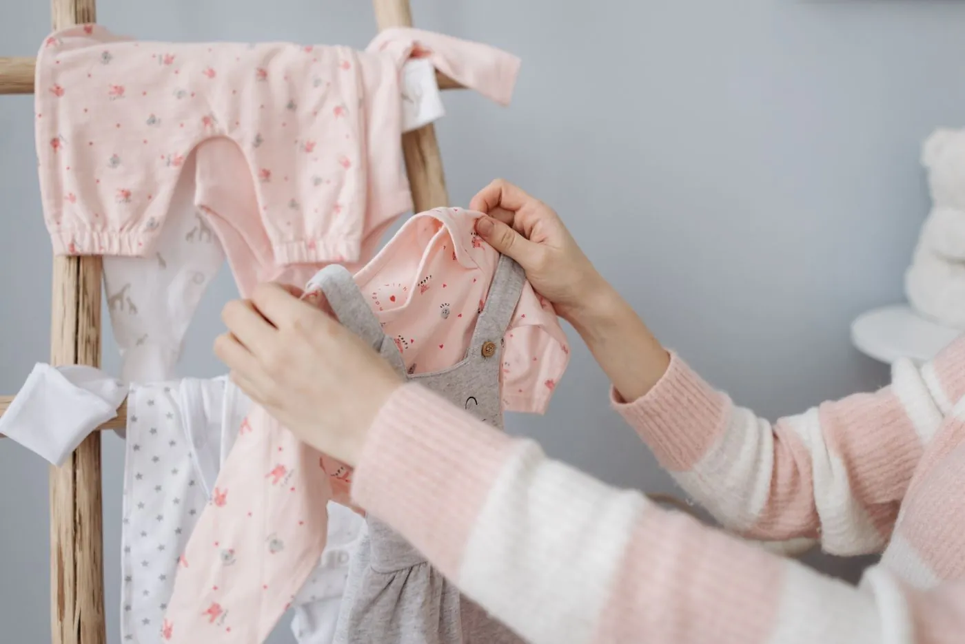 Ruce vybírají dětské body a oblečky zavěšené na ramínkách